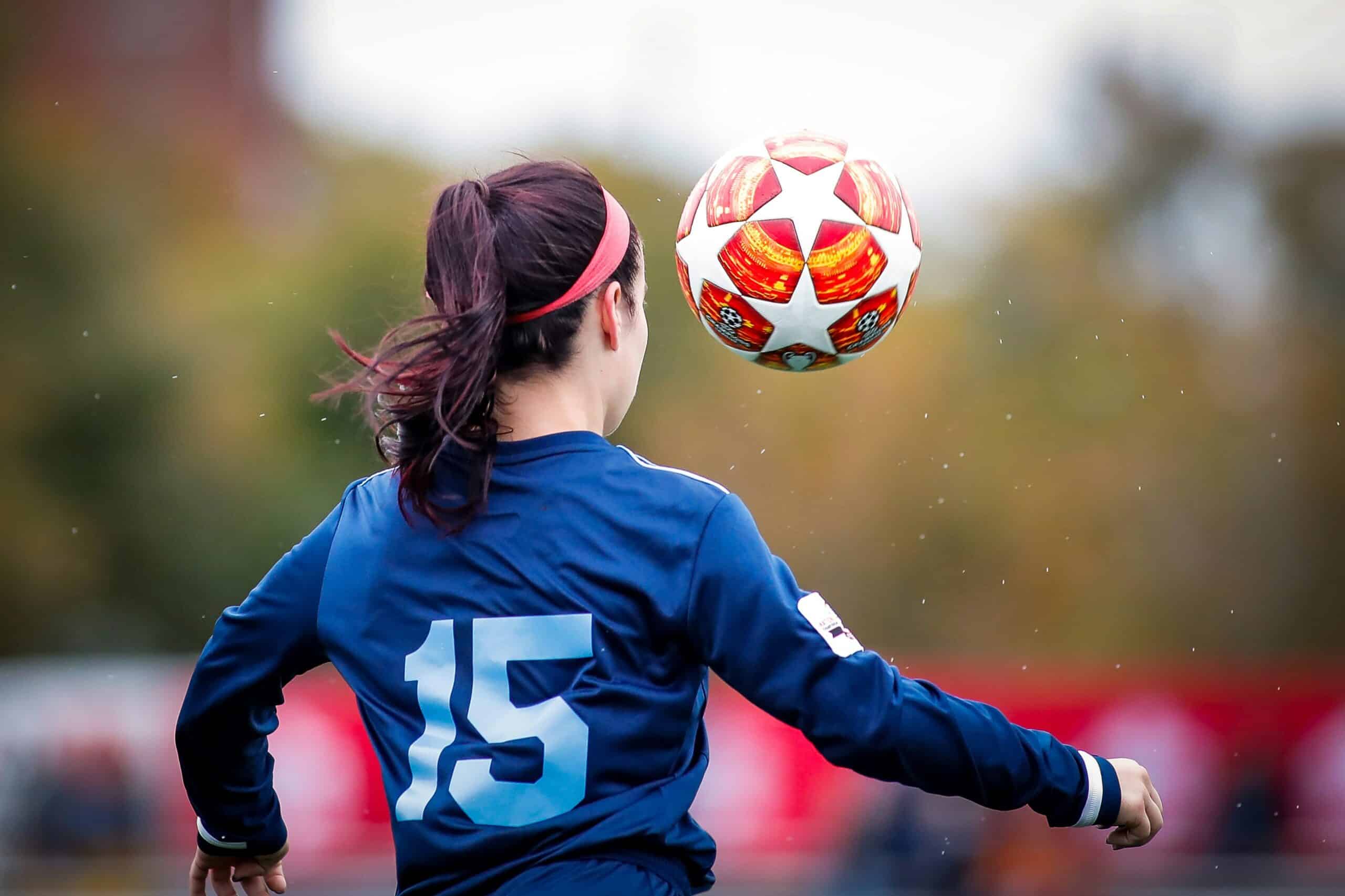 Mujer futbolista vista de espaldas mientras controla un balón
